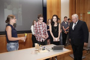 Unser Bild entstand bei der Präsentation des Projekts „Der programmierbare Tablettendosierer“. Reinhold Klüter (ganz rechts) von der Bezirksregierung Arnsberg nahm den Prototypen genau in Augenschein, links neben ihm Maria Azim, die als MINTorin und Mitarbeiterin aus der Arbeitsgruppe von Prof. Hans-Jürgen Christ die Siegergruppe „PeltoringSi“ betreute.